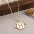 Gros plan d'un pendentif circulaire doré rotatif orné d'une lettre H en strass - 镶钻字母H款