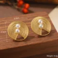 Détail macro de boucles d'oreilles rondes dorées avec perles et découpe géométrique - Boucles d'oreilles ajourées triangle à texture tressée (E4-20505-4500)