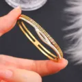 Primo piano di un bracciale dorato con motivo a meandro e intarsio di strass luminosi - Stile Greca (sz765) / Oro