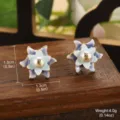 Gros plan de boucles d'oreilles fleurs en émail avec perle sur bois. (82 chars) - 淡蓝紫渐变渐变金边花朵人造珍珠款 / 1.3x1.3cm