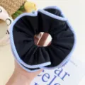 Detailed close-up of a large black fabric scrunchie with blue and white striped edges - Striped Edge Scrunchie / Black