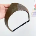 Detail view of the brown textured leather crown-shaped headband with adjustable strap. - Adjustable Size / Coffee