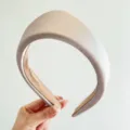 Gros plan d'un élégant serre-tête triangle rembourré en satin champagne pour femme - Abricot
