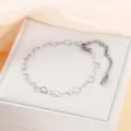 Detailansicht eines silbernen Herz-Edelstahlarmbands auf einer weißen Geschenkbox - Stahlfarben