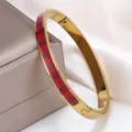 Detailansicht eines goldenen Titanstahl-Armreifs mit rotem Emaille-Karomuster. - Rotes Karo (sz819)
