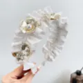 Détail d'un serre-tête blanc à volants orné de fleurs métalliques dorées et de perles. - Serre-Tête Plissé Fleur en Métal Perle / Blanc