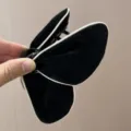 Detailed view of a black velvet butterfly hair claw clip with stylish white piping edge. - Butterfly Style (S378) / Black with White Edge
