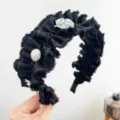Détail d'un élégant serre-tête noir à volants avec perle et breloques de fleurs argent - Serre-Tête Plissé Fleur Perle / Noir