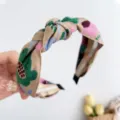 Gros plan détaillé montrant la broderie florale et le nœud d'un bandeau beige ethnique - Serre-tête Noué à Fleurs Brodées / Kaki