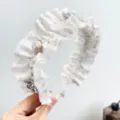 Gros plan détaillé d'un serre-tête blanc à volants avec perles et fleurs - Serre-Tête Plissé Fleur Perle / Blanc