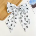 Gros plan d'un grand nœud à cheveux en mousseline blanche avec motifs noirs - Impression Nœud Blanc