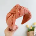 Detailopname van een koraalrode geknoopte stoffen hoofdband met fonkelende strass - Strass Knoop Stijl / Oranje