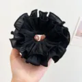 Nahaufnahme eines übergroßen schwarzen Organza-Haargummis mit elegantem Rüschendesign - Doppelt Gerüschter Scrunchie / Schwarz