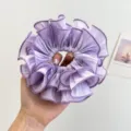 Detailaufnahme eines großen, plissierten lila Haargummis mit feiner Stofftextur - Doppelt Gerüschter Scrunchie / Lila