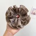 Detaillierte Nahaufnahme eines übergroßen plissierten Haargummis in Taupe mit Goldpaspel. - Doppelt Gerüschter Scrunchie / Braun