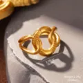 Detailaufnahme eines goldenen Titanstahlrings mit ovalem Design auf einem Stein. - Ovale Verflochtener Stil (STR-0049-1800) / Gold