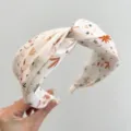 Detail view of a cream wide headband with autumn floral and leaf patterns in soft satin. - Twist Knot Style (S180) / Beige National Wind Print