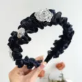 Detailansicht eines schwarzen Rüschen-Stirnbands mit dekorativen silbernen Rosen. - Schwarz
