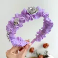 Nahaufnahme eines lila Rüschen-Haarreifs mit metallischen silbernen Rosen-Details - Lila