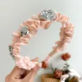 Detailansicht eines rosa gerüschten Haarreifs mit silberner Rose und metallischen Perlen - Rosa