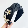 Close-up detail of a black satin knotted headband with 3D metallic flower decorations. - 3D Rhinestone Flower Knotted Headband / Black