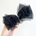 Vista detallada de un elegante lazo para el cabello de organza negra con centro de strass brillante. - Pinza de Resorte con Lazo / Negro
