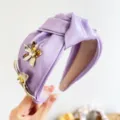 Detailed view of elegant purple satin knotted headband featuring 3D gold metal flowers - 3D Rhinestone Flower Knotted Headband / Purple