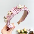 Elegant pink pleated headband featuring detailed gold metallic flowers and white pearls - Pink
