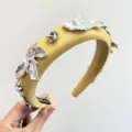 Vue rapprochée d'un serre-tête rembourré jaune orné de breloques en métal argenté. - Jaune