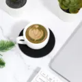 Top view of a black round felt coaster under a white coffee cup on a desk - Round / Black