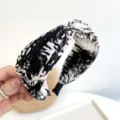 Close-up detail of a stylish knotted fabric headband with black and white tie-dye pattern. - Cross Headband / Black and White Tie-Dye Criss Cross Headband