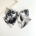 Detail view of a black and white tie-dye fabric bow hair accessory with ink splash pattern - Bowknot Spring Clip / Black and White Tie-Dye Bow Spring Clip