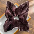 Close-up detail of a coffee brown velvet pleated scrunchie hair tie on a wooden tray. - AB Side Square Scarf Hair Tie