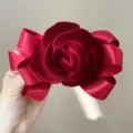 Close-up of elegant burgundy velvet rose hair clip with satin ribbon bow details. - Burgundy