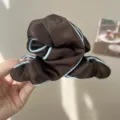 Detail view of coffee brown fabric hair scrunchie with light blue contrast piping - Pleated Edged Claw Clip