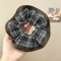 Nahaufnahme eines blau-braunen Karo-Haargummis mit einem eleganten braunen Satin-Rand - 咖边发圈 / Blau-Braun Karomuster