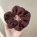 Detailed macro shot of a textured brown tweed scrunchie with elegant light blue piping - Scrunchie