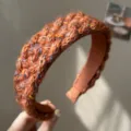 Detailed close-up showing the colorful braided yarn texture of this wide knitted headband - Knitted Headband / Orange