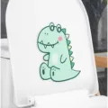 Dettaglio di un adesivo deodorante in feltro a forma di dinosauro verde su WC bianco - Dinosauro / 15*13cm