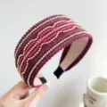 Dettaglio di un'elegante fascia larga bordeaux con perle dorate e paillettes scintillanti. - Stile Largo con Righe di Perline e Luccichio / Rosso