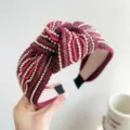 Primo piano di un cerchietto annodato bordeaux con perline dorate e dettagli in paillettes - Stile Annodato con Righe di Perline e Luccichio / Rosso