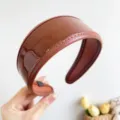 Detail shot of the vintage brown glossy PU leather wide headband with stitching. - Leather Wide Headband / Coffee