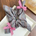Dettaglio macro di un elastico a scacchi blu e marroni con graziosi fiocchi vichy rossi - Scrunchie Sciarpa Quadrata (Decoro Fiocco) / Quadri marroni