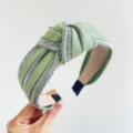 Dettaglio ravvicinato di un cerchietto a nodo verde chiaro con brillanti strass argentati. - Stile Annodato / Verde