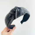 Primo piano di un cerchietto nero con nodo, decorato con strass lucenti e trame verticali - Stile Annodato / Nero