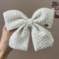 Detailed macro shot of a cream tweed bow hair clip decorated with shiny gold sequins - Hair Bow