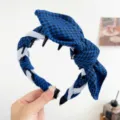Detail showing the blue houndstooth bow and twisted design on a stylish headband - Rabbit Ears + Tooth Comb Headband / Blue & Black Plaid