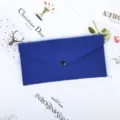 Close-up of a royal blue felt envelope-style pouch featuring a black snap button closure - Blue