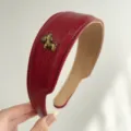 Détail du serre-tête large en cuir rouge vintage avec une breloque poney dorée - Bandeau Cuir Cheval / Rouge