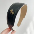 Gros plan d'un serre-tête en cuir noir vintage avec décoration de cheval doré - Bandeau Cuir Cheval / Noir